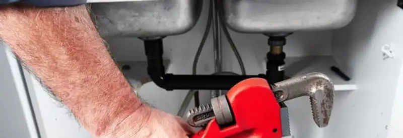 Garbage disposal repair technician tightening drain connections under a kitchen sink in Detroit, MI