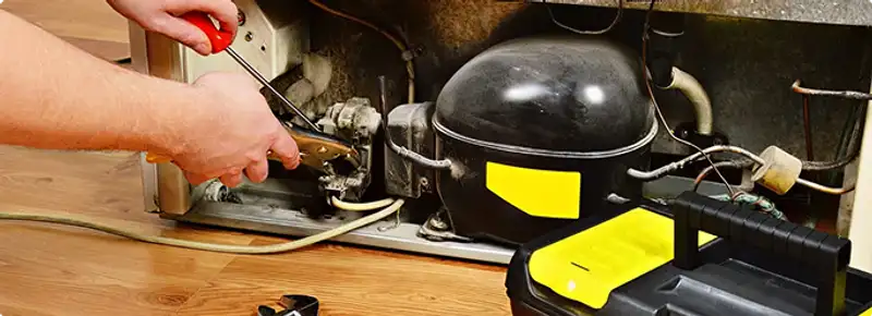 Refrigerator repair technician fixing the compressor and wiring in Dearborn, MI