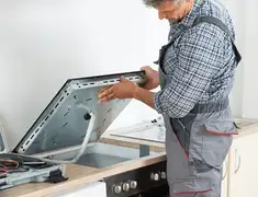 Appliance repair technician installing a built-in cooktop in Detroit, MI