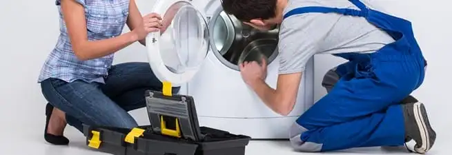 Washer repair technician inspecting a front-load washing machine with tools in Detroit, MI