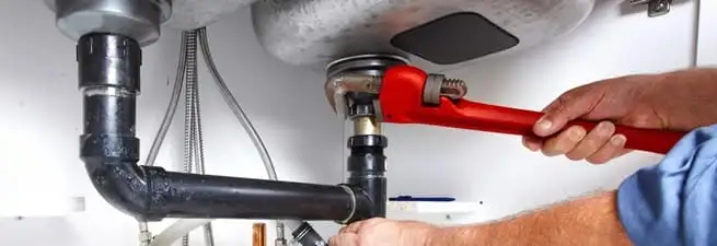 Garbage disposal repair technician tightening the sink drain and disposal connection in Detroit, MI