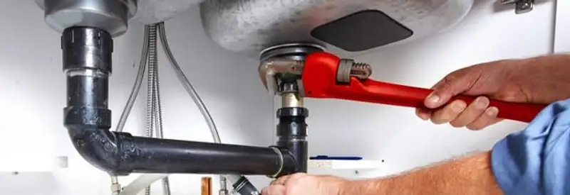 Garbage disposal repair technician tightening the sink drain and disposal connection in Detroit, MI