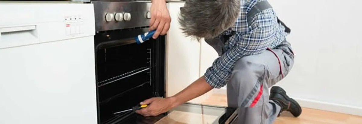Oven repair technician inspecting and servicing an electric oven in Detroit, MI