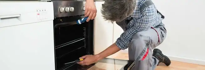 Oven repair technician inspecting and servicing an electric oven in Detroit, MI