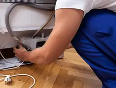 Appliance repair technician fixing refrigerator water line and connections in Detroit, MI