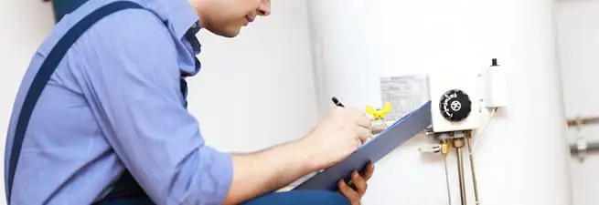 Water heater repair technician inspecting the unit and recording service notes in Detroit, MI