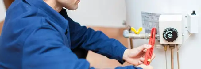 Water heater repair technician adjusting the temperature control and gas valve in Detroit, MI
